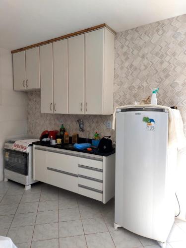 a kitchen with white cabinets and a white refrigerator at Brilho do Sol in Guarapari