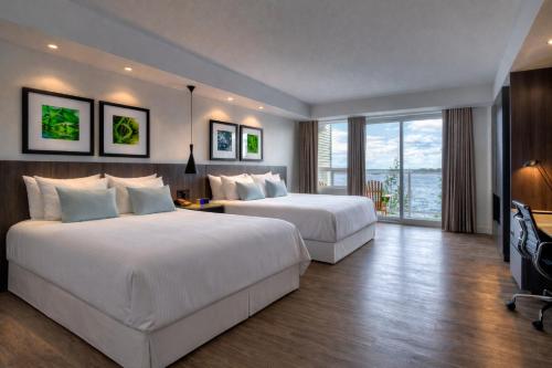 two beds in a hotel room with a large window at Taboo Muskoka in Gravenhurst