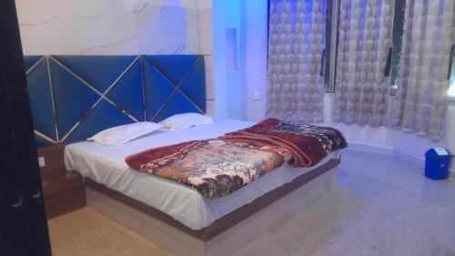a bed with a blue headboard in a room at Hotel om banna in BhÄdura