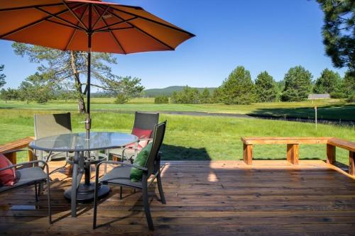 a table and chairs on a wooden deck with an umbrella at 63 Meadow House in Sunriver
