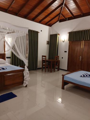 a bedroom with two beds and a table and chairs at Nature Velora Villa in Tangalle