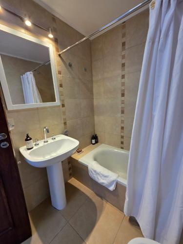 a bathroom with a sink and a bath tub with a mirror at Caseros Centro Salta in Salta