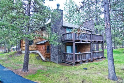 a log house with a balcony and trees at 62 Wildflower in Sunriver