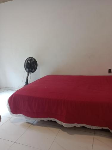 a bedroom with a red bed and a fan at Renascer in São Pedro da Aldeia