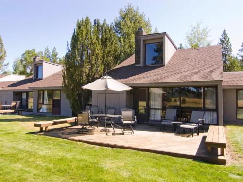 a house with a deck with a table and an umbrella at 61 Meadow House in Sunriver
