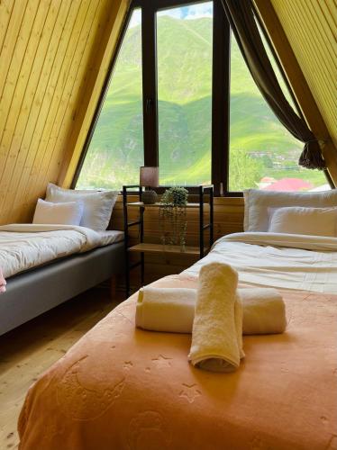 two beds in a room with a large window at River View Cabin Kazbegi in Kazbegi