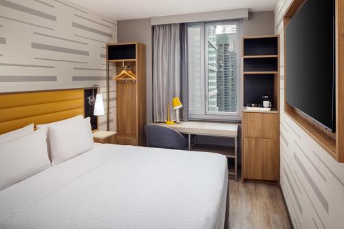 a bedroom with a bed and a desk and a television at Hampton Inn by Hilton New York Times Square in New York