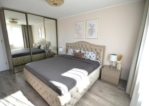 a bedroom with a large bed and a mirror at E.D. Luxury Apartaments in Šiauliai