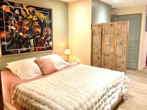 a bedroom with a bed with a large painting on the wall at Maisonnette Cosy Villa Ajna in Bayonne