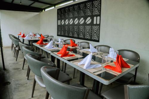 a row of tables and chairs with red and white napkins at Migano Hotel in Ruhengeri