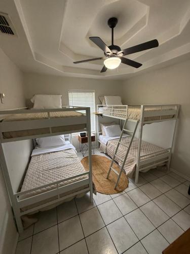 a room with three bunk beds and a ceiling fan at PEBBLES' BEACH HOUSE in Edinburg