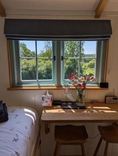 a window in a room with a table with flowers on it at Cornish Valley Retreat in Bodmin