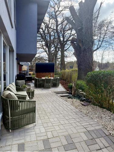 a patio with chairs and tables and a tree at Ferienhaus TRAUM AM SEE mit Sauna und Whirlpool in Zislow