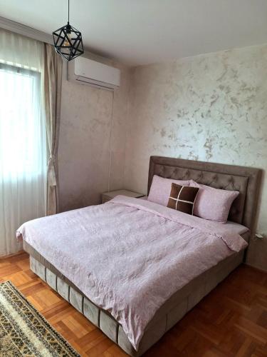 a bedroom with a large bed with pink sheets at Apartment Harmony in Plužine