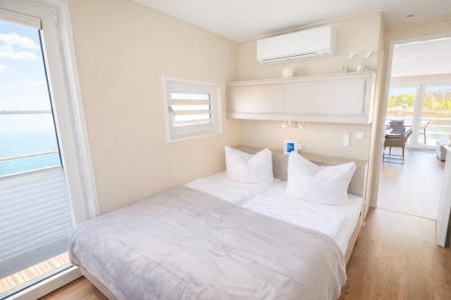 a white bed in a room with a large window at Floatinghouse Möwe 2 - LP2 in Vetschau