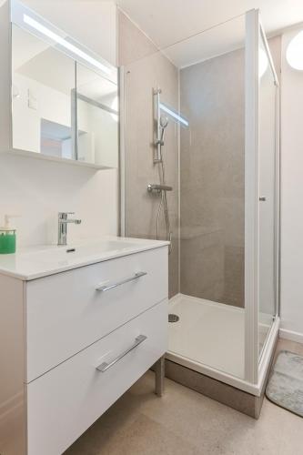 a white bathroom with a shower and a sink at Cosy app near sea in Cabourg