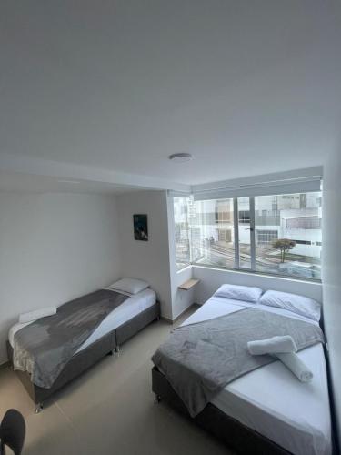 two beds in a room with a window at Hotel Portal Del Cerro Manizales in Manizales