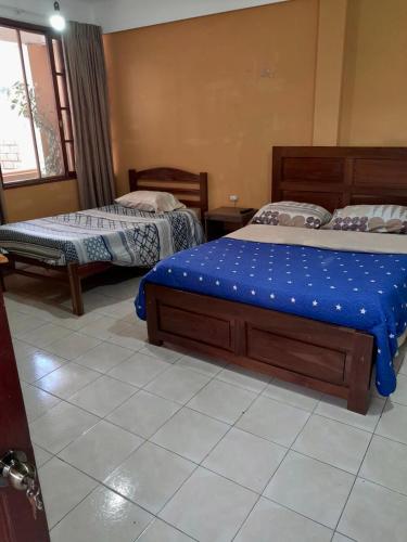 a bedroom with two beds and a window at Hostal Urbano in Tarija