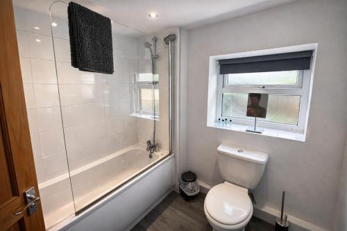 a bathroom with a toilet and a tub and a window at Urban in Southampton