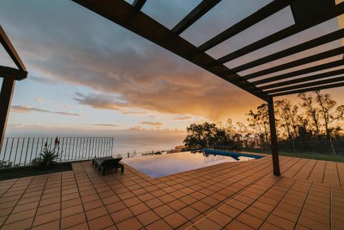 a swimming pool with a sunset in the background at Ocean View Villa in Funchal