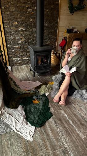 a man reading a book in front of a fireplace at Apart Garden з чаном-джакузі in Slavske