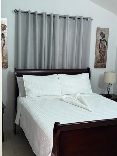 a bedroom with a bed with white sheets and a curtain at Trelawnys Bliss Escape in Spring Rises