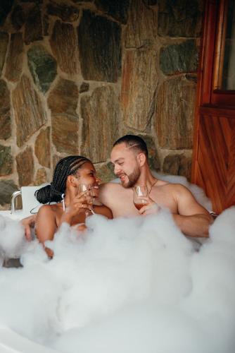 a man and woman sitting in a bath tub with wine glasses at Zirwa Hotel Boutique - Dentro del Parque Tayrona in El Zaino