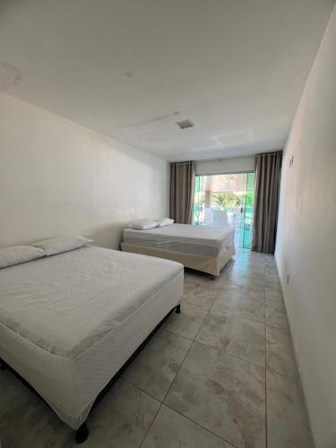 a bedroom with two beds and a large window at Casa Brisa do Mar in Cabedelo