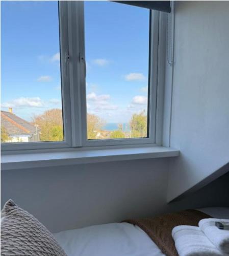 a window in a room with a bed looking out at Karibu - Boutique Cottage with Parking - Short walk to Beach in St Ives