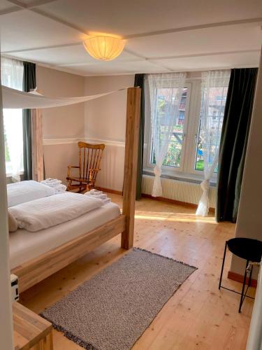 a bedroom with a bed and a chair and windows at Villa Epoka in Interlaken