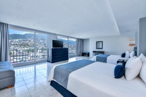 a hotel room with two beds and a large window at Krystal Beach Acapulco in Acapulco
