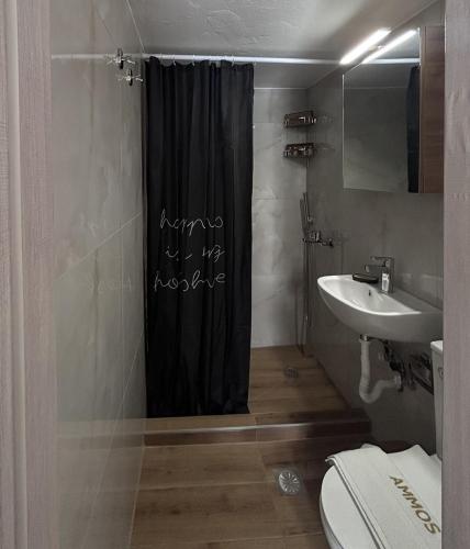 a bathroom with a black shower curtain and a sink at Ammos in Kavála