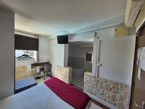 a room with a bedroom with a bed and a bathroom at Hôtel Le Floreal in Trèbes