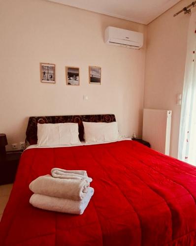 a bedroom with a red bed with towels on it at Nàra house in Áyios Spirídhon
