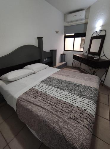 a bedroom with a bed with a mirror and a desk at Invernadero Inn in Veracruz