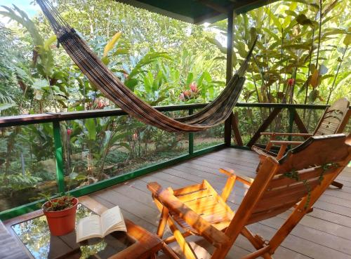 a hammock and a chair on a deck with books at Musas Garden Lodge Tambopata in Puerto Maldonado