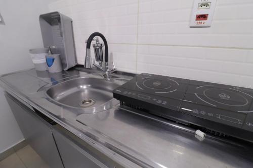 a kitchen counter with a stove and a sink at Studio III - Centro Jundiaí - Ar Condicionado in Jundiaí