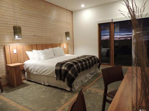 a bedroom with a bed, chair, and a window at Hotel Simple Patagonia in Puerto Natales