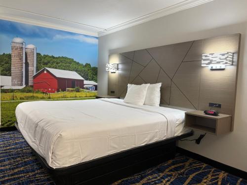 a bedroom with a large bed with a red barn at Travelodge by Wyndham Odessa in Odessa