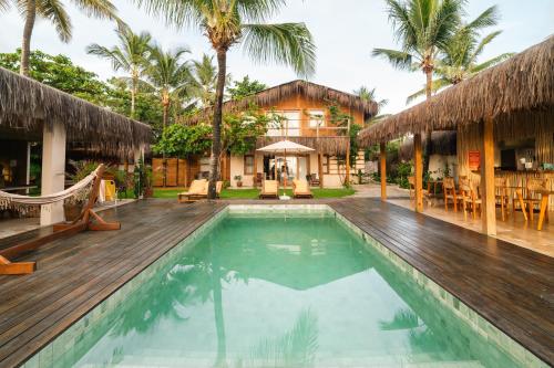 a villa with a swimming pool and a house at Pousada D'Oxum Caraíva in Caraíva