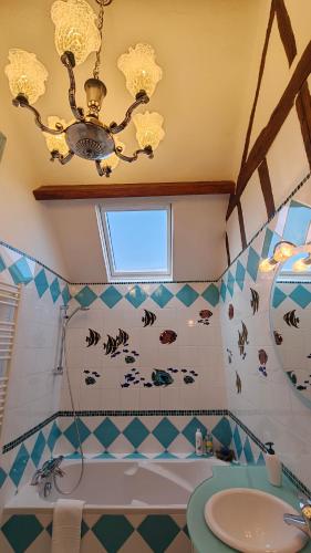 a bathroom with a chandelier and a tub and a sink at Le Relais de la Tour in La Chaussée-Saint-Victor