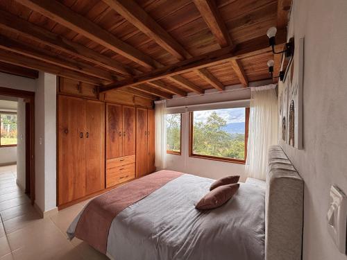 a bedroom with a large bed with a large window at Cabaña Villa Serena in Villa de Leyva