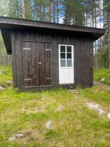 a wooden shed with a door in the grass at Holmsjøhytta in Sjørbotn