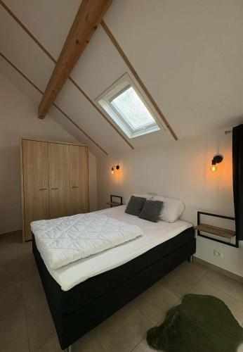 a bedroom with a large bed with a skylight at Maison des Fées d'Achouffe in Houffalize
