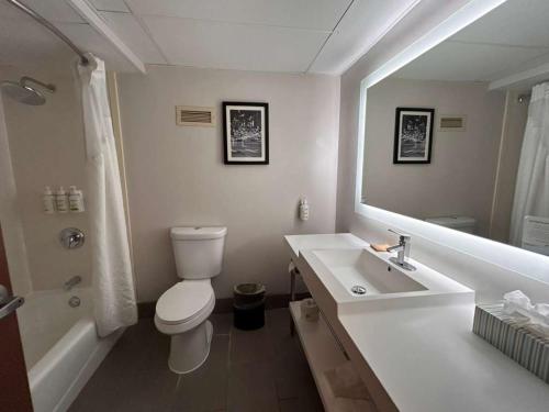 a bathroom with a sink and a toilet and a mirror at Urbana Hotel Conference Center in Urbana