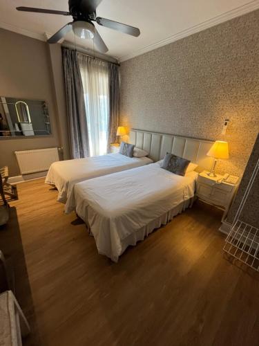 a bedroom with two beds and a ceiling fan at Mito Casa Hotel in Santiago