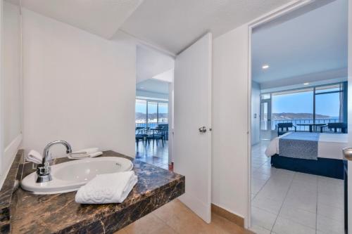 a bathroom with a sink and a bedroom with a bed at Krystal Beach Acapulco in Acapulco