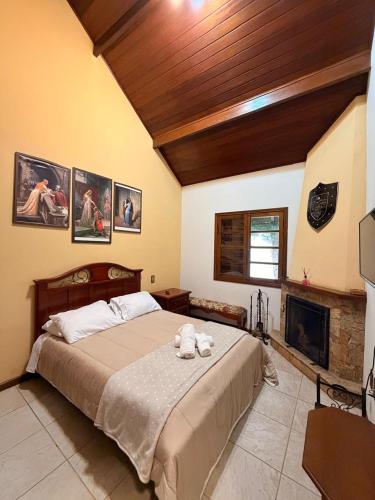 a bedroom with a large bed and a fireplace at Recanto da Neblina in Monte Verde