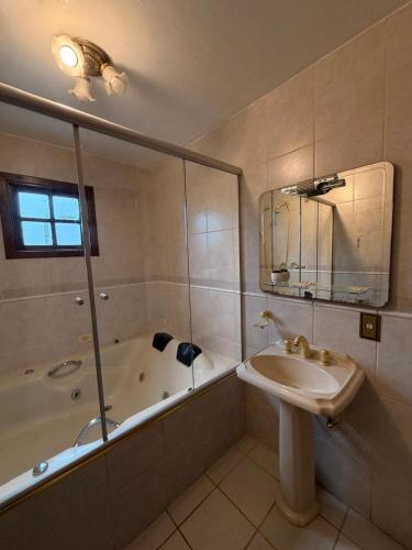 a bathroom with a sink and a tub and a mirror at Recanto da Neblina in Monte Verde