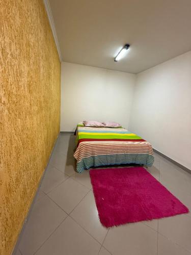 a room with a bed with a pink rug on the floor at Hostel em SJC perto da rodoviária, centro,Embraer e cta in São José dos Campos
